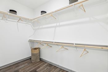 A white closet with wooden hangers and a brown bag on the floor.